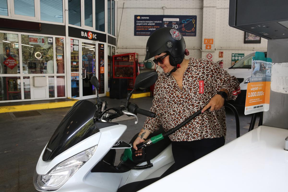 Una conductora rellena el tanque de combustible de su moto, en una gasolinera de Barcelona. 