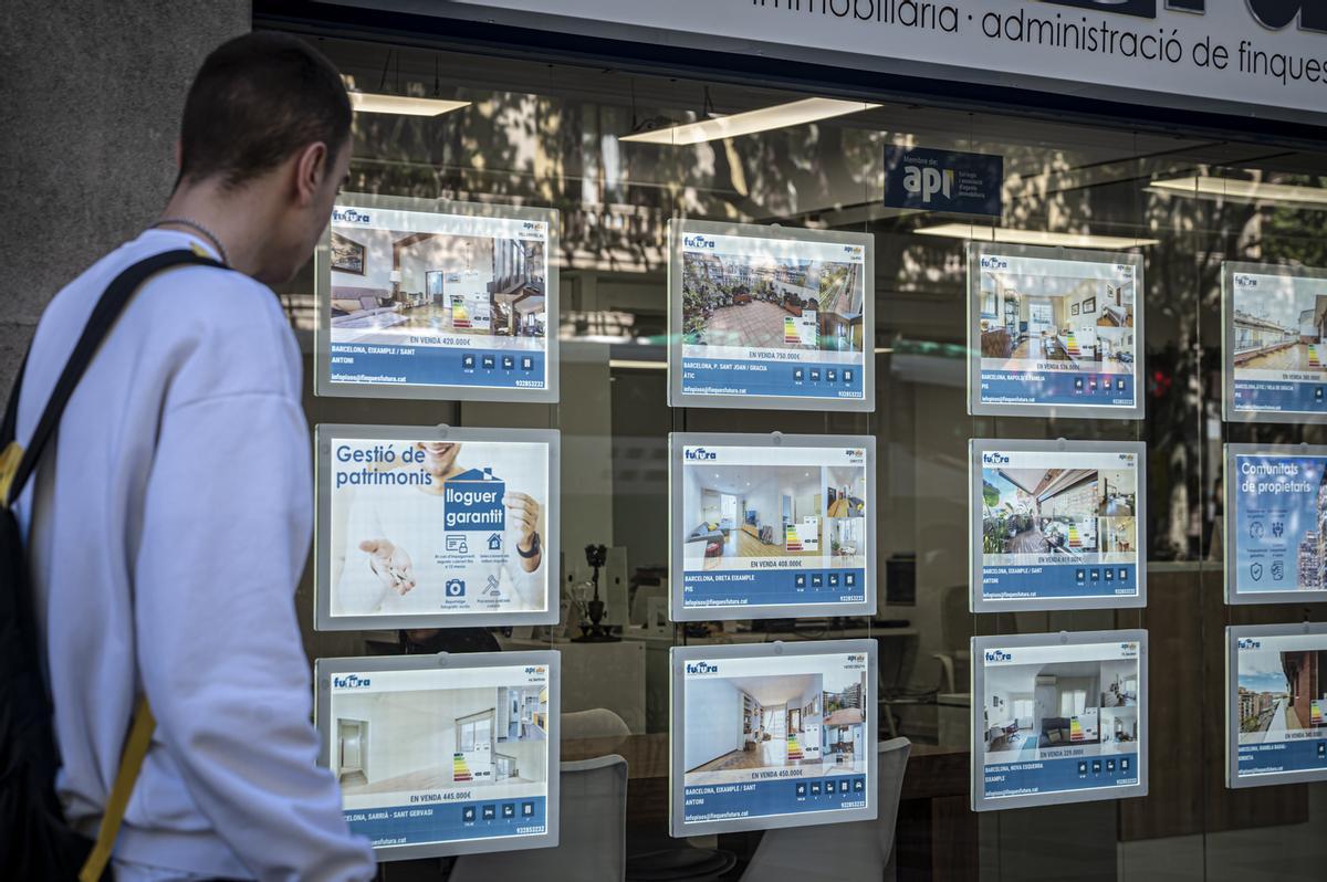 Un joven consulta los carteles de una inmobiliaria en Barcelona.