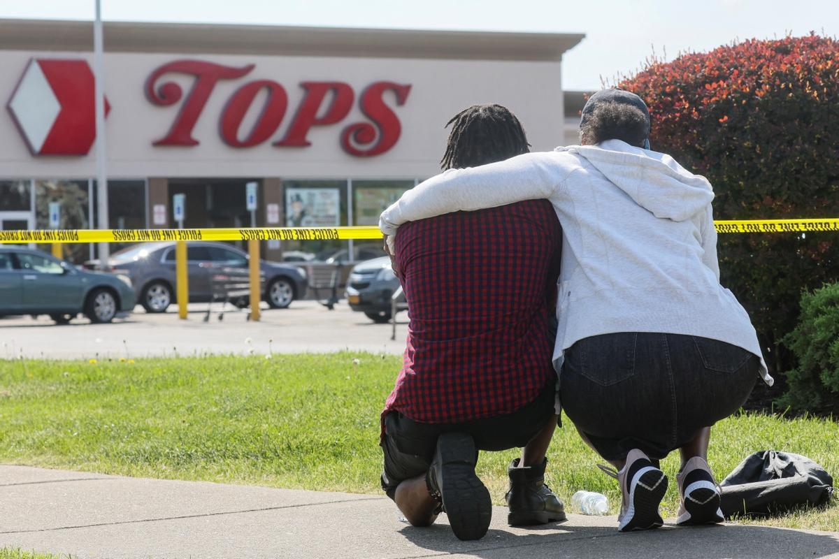 Una pareja arrodillada en las cercanías del supermercado de Búfalo donde se produjo la matanza.