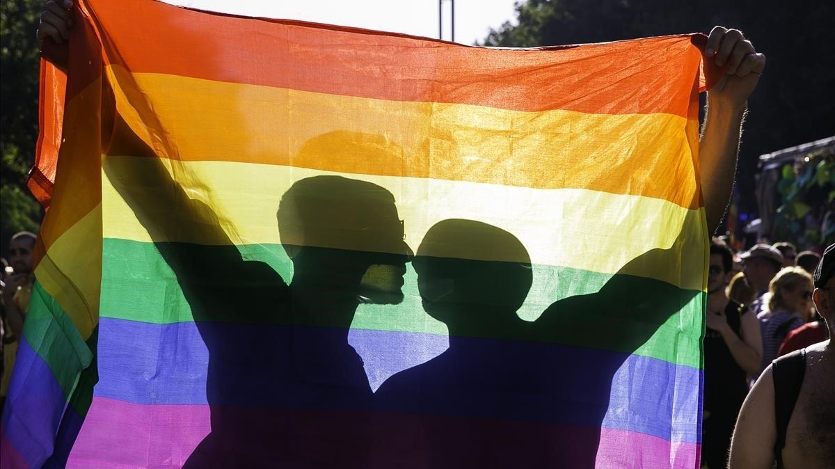 Una pareja se besa tras una bandera arcoíris durante la manifestación del orgullo LGBTI+ del pasado junio en Barcelona Una pareja se besa tras una bandera arcoíris durante la manifestación del orgullo LGBTI+ del pasado junio en Barcelona
