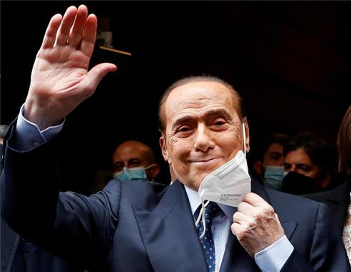 El ex primer ministro italiano Silvio Berlusconi se quita la mascarilla y saluda a su llegada al Palacio de Montecitorio en febrero para las conversaciones sobre la formación de un nuevo gobierno.