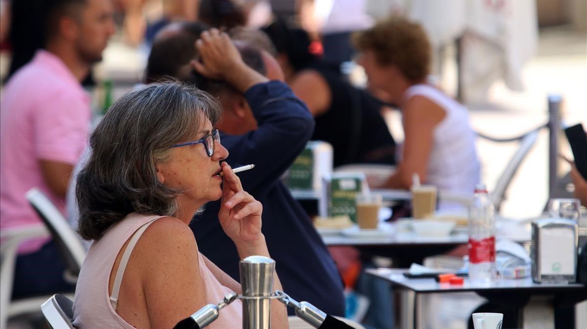 Una mujer fumando en una terraza. Una mujer fumando en una terraza.