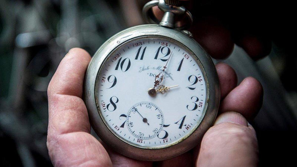 Un hombre cambia la hora en un reloj de bolsillo antiguo.
