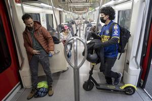 Un usuario de patinete, el 19 de diciembre, en el interior de un vagón de Ferrocarrils, en la parada de Espanya
