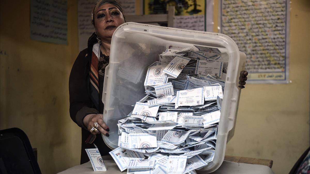 Una miembro de una mesa electoral muestra las papeletas depositadas en una urna en El Cairo.