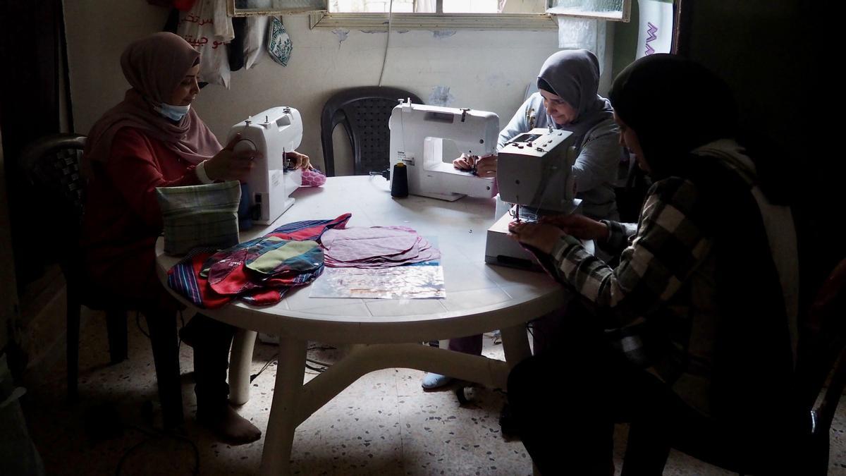 Doua, Rima y Mariam usan la última luz del día que entra por la ventana para coser compresas de tela para la oenegé WingWoman Lebanon. 