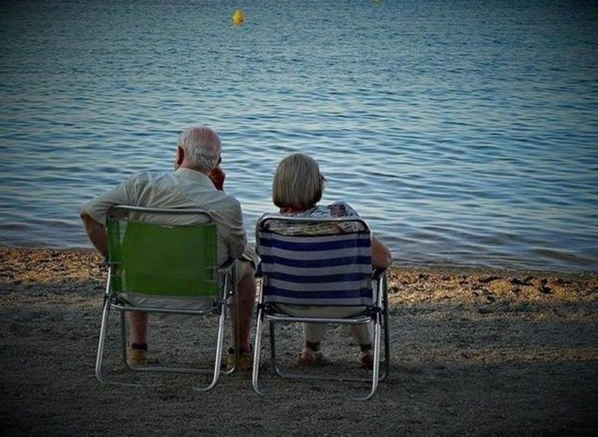 Dos abuelos se relajan en una playa. 