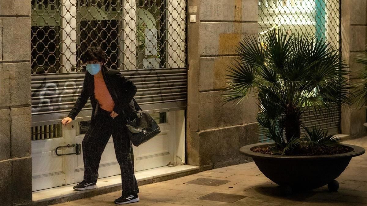 Una mujer con mascarilla echa el cierre a su negocio, el pasado 27 de octubre, en Barcelona. Una mujer con mascarilla echa el cierre a su negocio, el pasado 27 de octubre, en Barcelona.