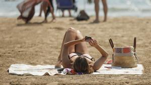 Una mujer utilizando el móvil en la playa.