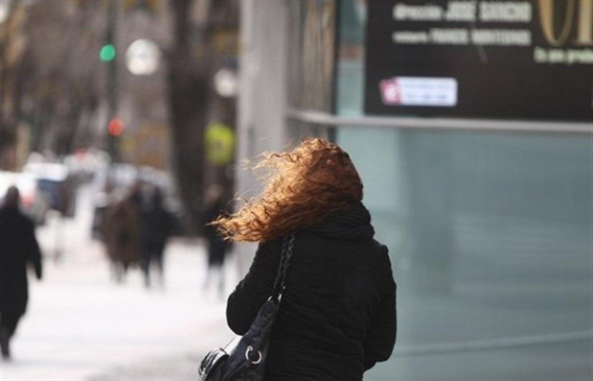  Una mujer afectada por el frío y los fuertes vientos.
