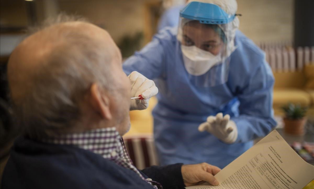 Una voluntaria de Open Arms realiza un test de detección de coronavirus a un anciano en una residencia de Barcelona. 