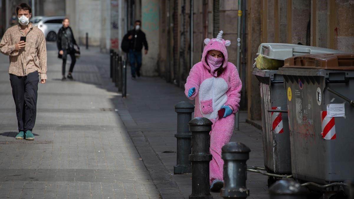 Una mujer con un traje de unicornio y protegida con mascarilla y guantes en Barcelona.