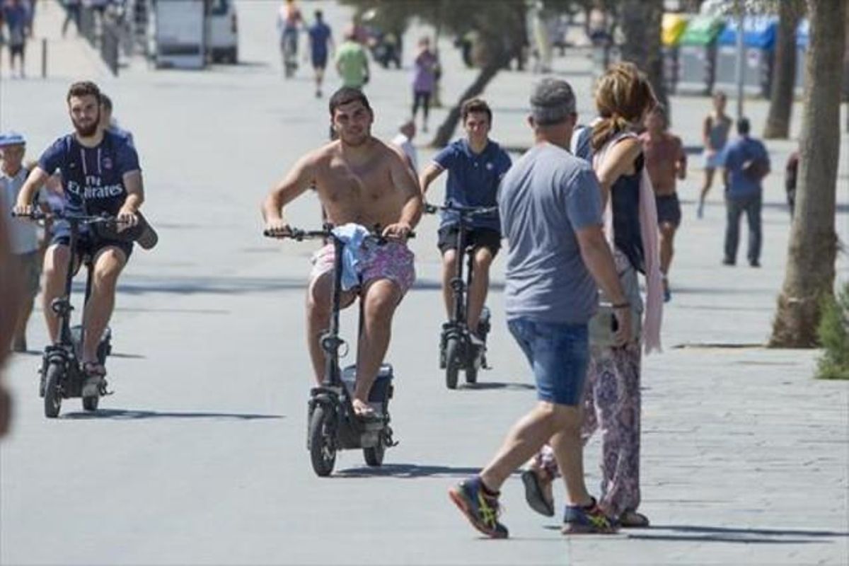 Tres usuarios de patinete eléctrico, en el paseo marítimo de la Barceloneta. Tres usuarios de patinete eléctrico, en el paseo marítimo de la Barceloneta.