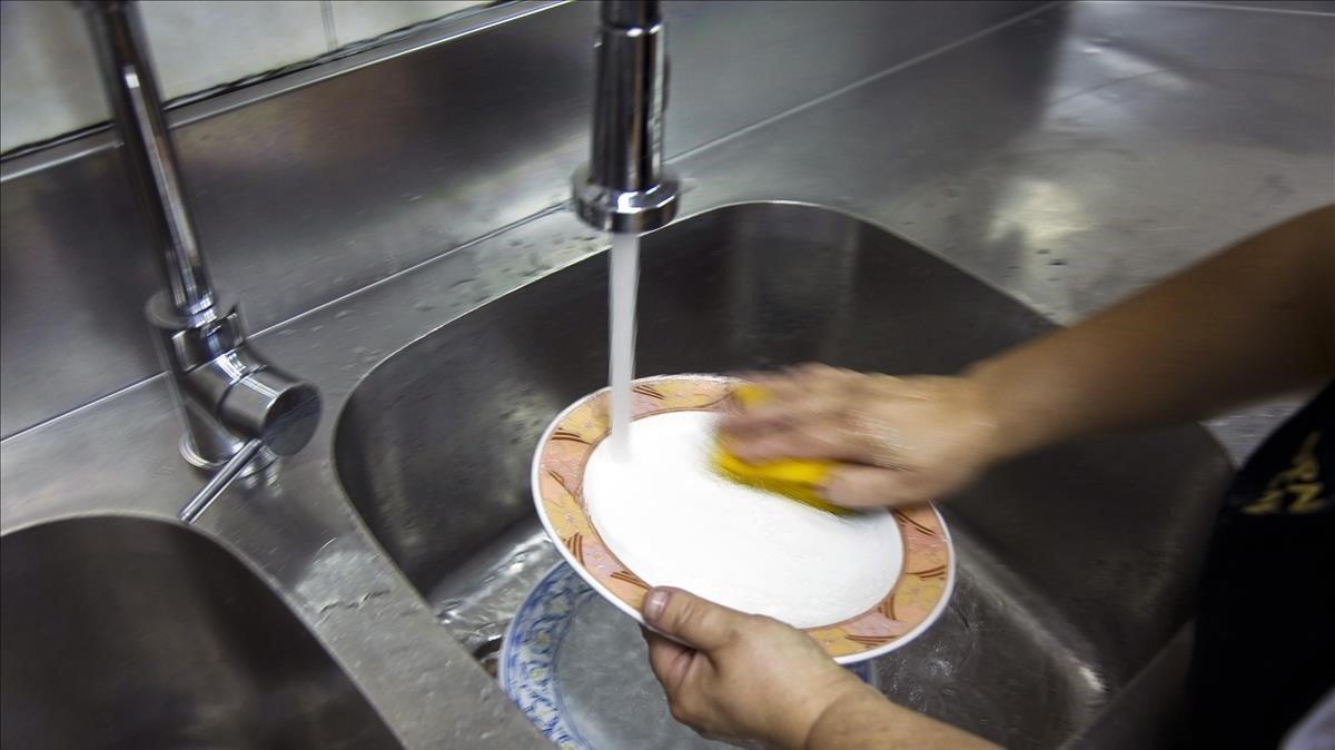 Una persona lava platos en un establecimiento de Barcelona.