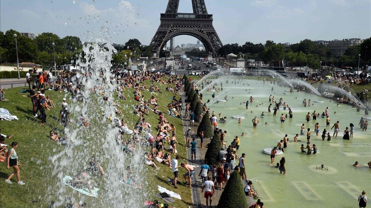 Franceses y turistas, bañándose en las fuentes junto a la torre Eiffel para combatir la canícula, este jueves. 