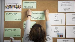La directora de La Palmera, Conchi Calvo, coloca un cartel de bienvenida, en inglés y ucraniano, en el aula de acogida.