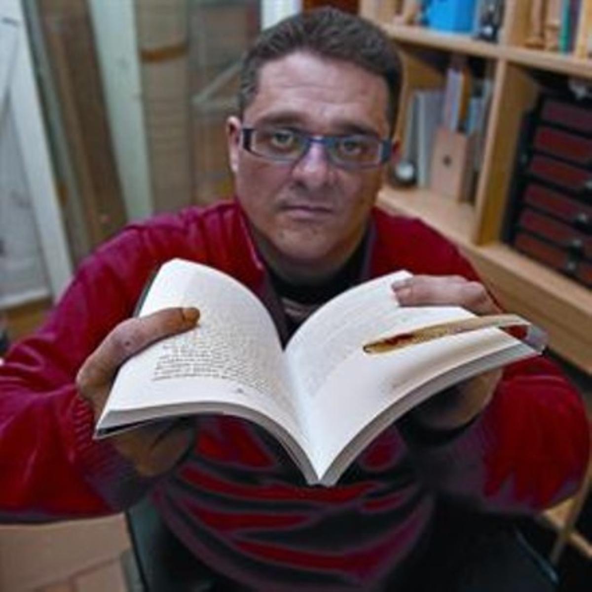 Fernando Sánchez muestra con orgullo su marcapáginas en un libro.