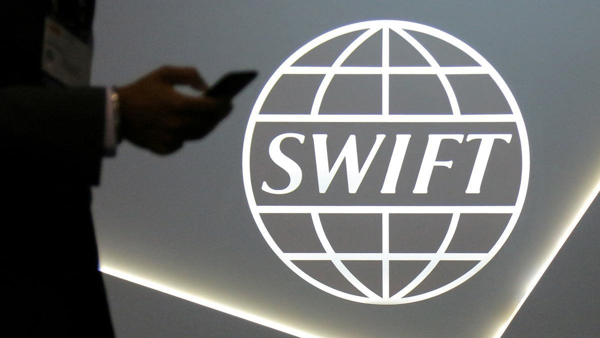 Un hombre que usa un teléfono móvil ente el logo de la cooperativa global de servicios de mensajería financiera segura SWIFT en la conferencia bancaria y financiera SIBOS en Toronto