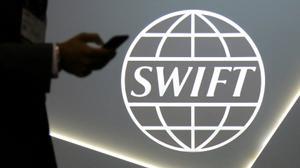 Un hombre que usa un teléfono móvil ente el logo de la cooperativa global de servicios de mensajería financiera segura SWIFT en la conferencia bancaria y financiera SIBOS en Toronto