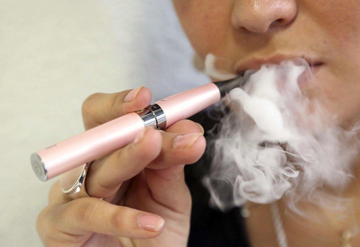 Una mujer fuma un cigarrillo electrónico. Una mujer fuma un cigarrillo electrónico.
