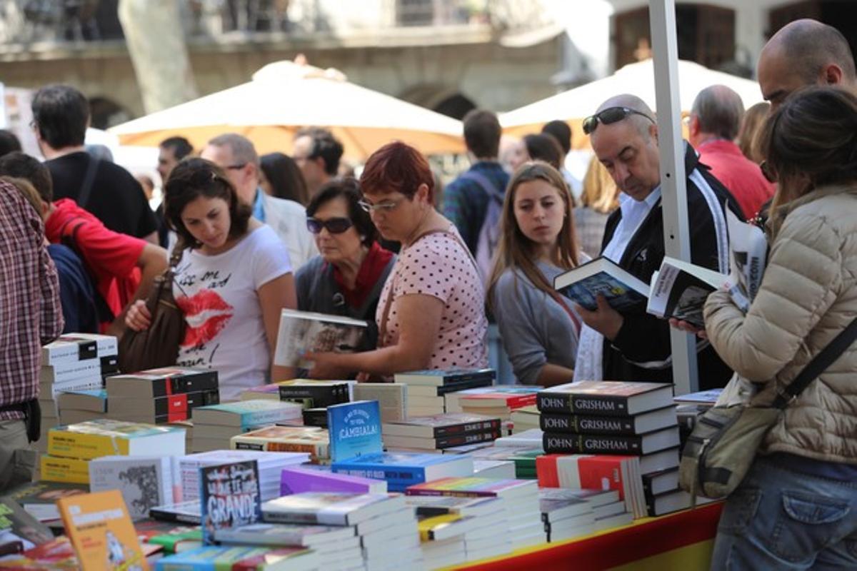 Unos lectores repasan libros en los puestos de venta que inundan Barcelona en una Diada de Sant Jordi.