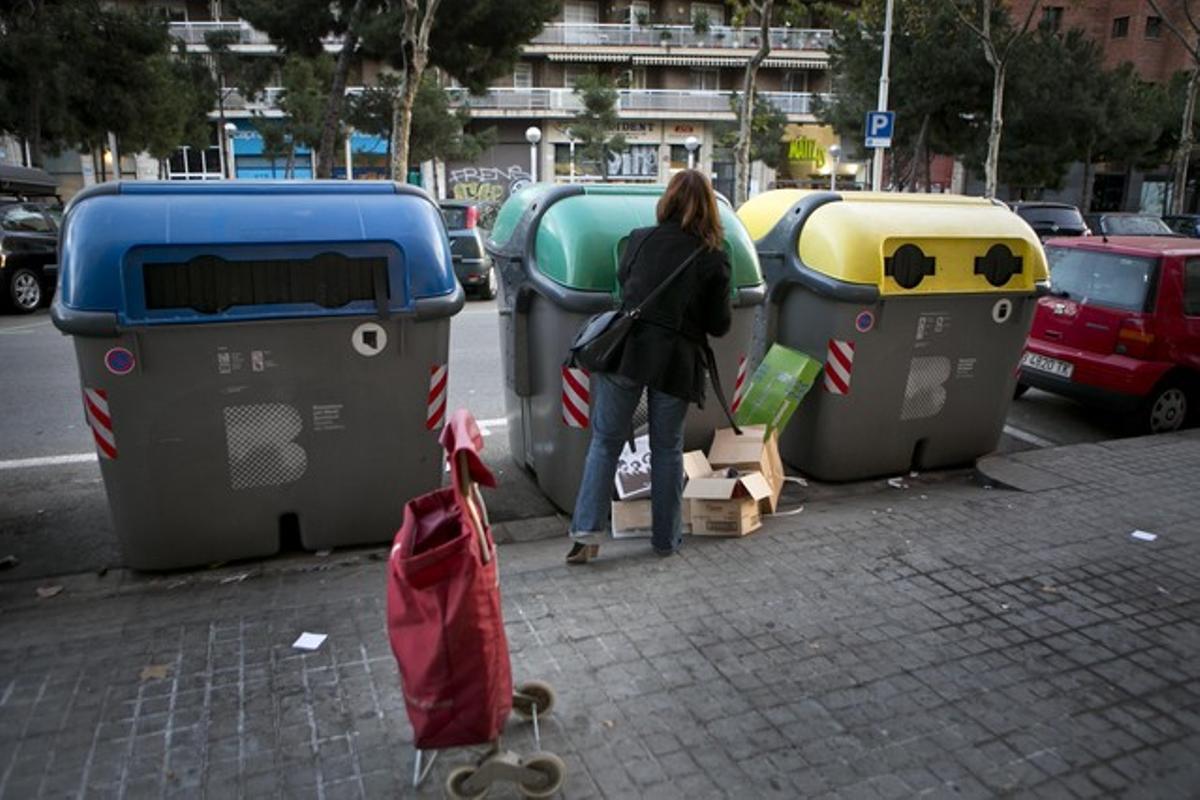 Una mujer deposita residuos en contenedores en Barcelona.