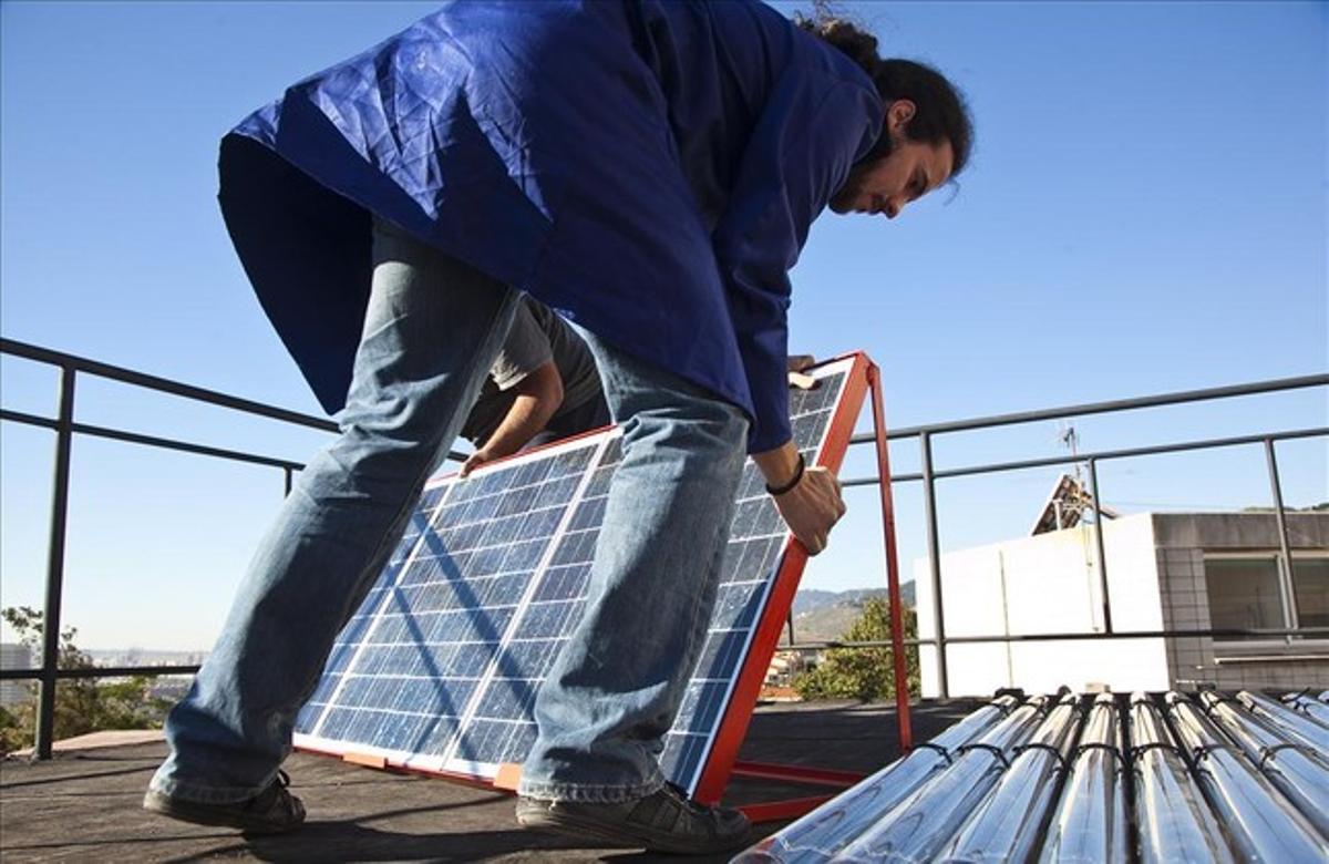 Un hombre instala placas fotovoltaicas en la cubierta de un edificio. Un hombre instala placas fotovoltaicas en la cubierta de un edificio.