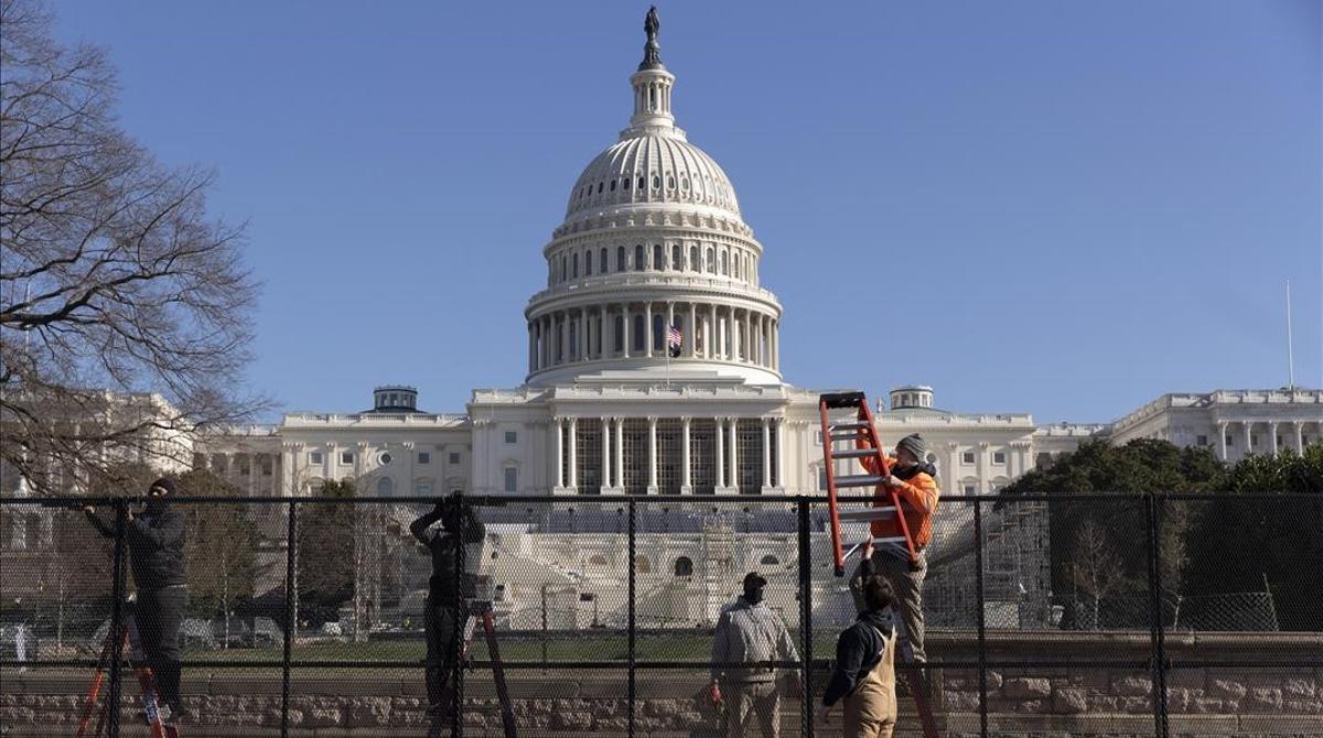 Trabajadores levantan una valla metálica alrededor del Capitolio.