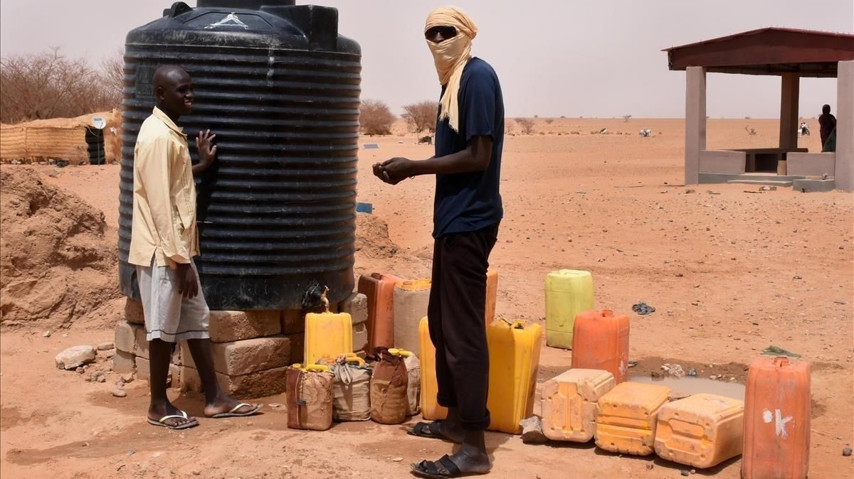 Dos refugiados recogen agua en un tanque en un campo de Níger. Dos refugiados recogen agua en un tanque en un campo de Níger.