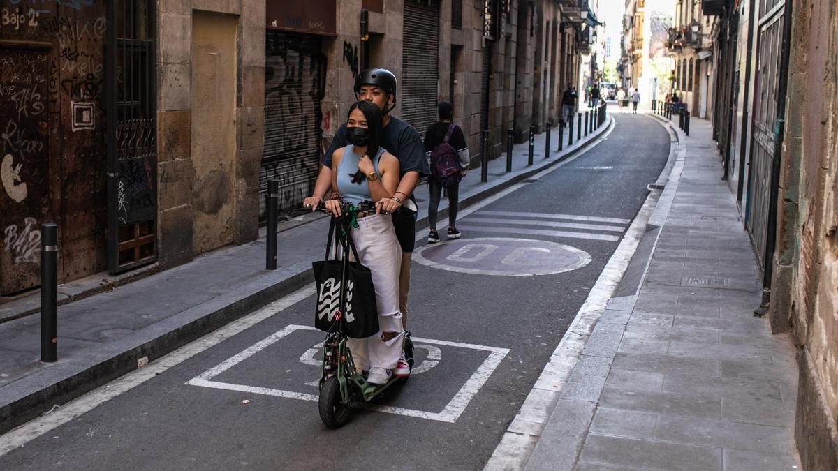 Un patinete por una calle de Barcelona con dos ocupantes
