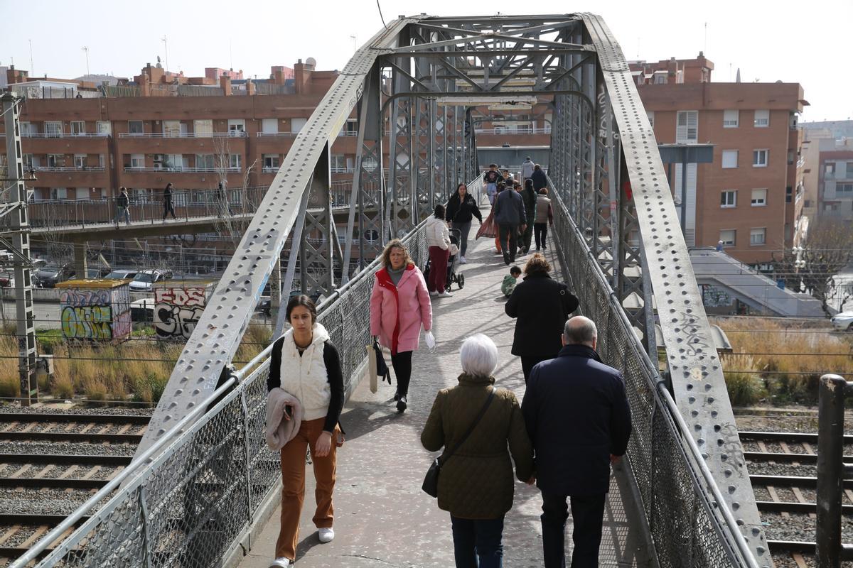 Vecinos de L’Hospitalet cruzan las vías de tren sobre el Pont d’en Jordà, que une los barrios de la Torrassa y Santa Eulàlia.