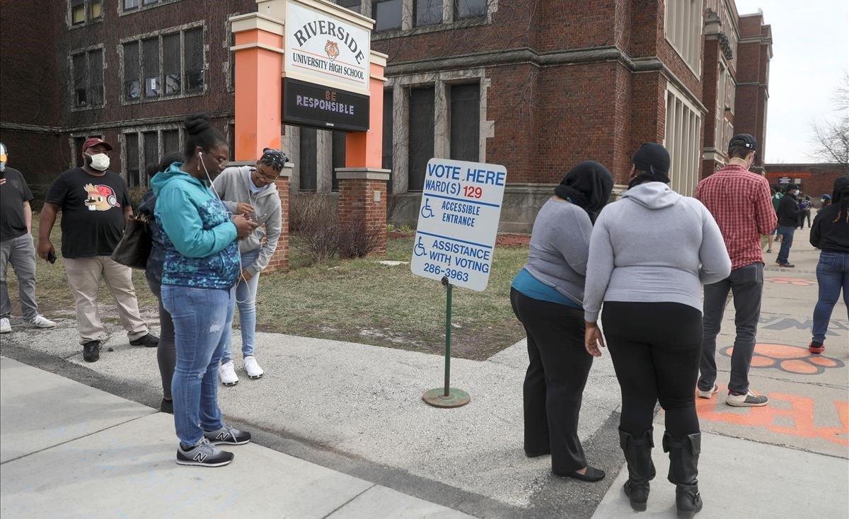 Votantes hacen cola en los alrededores de la Universidad Riverside, en el marco de las elecciones primarias presidenciales celebradas en medio del brote del covid-19, en Milwaukee, Wisconsin.