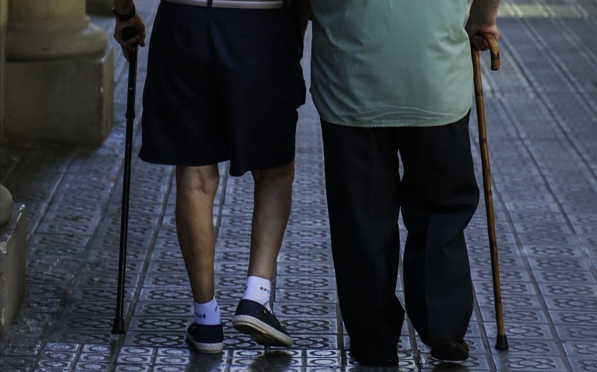 Dos ancianos pasean por una calle. Dos ancianos pasean por una calle.