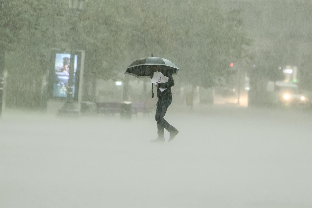 Un hombre camina bajo la lluvia intensa