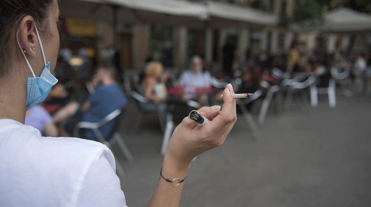 Una mujer fuma alejada de los clientes de una terraza de Barcelona, el pasado 18 de agosto. Una mujer fuma alejada de los clientes de una terraza de Barcelona, el pasado 18 de agosto.