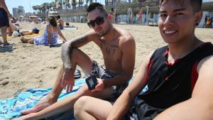 Dos jóvenes escuchan música en la playa con un altavoz inalámbrico, esta semana en Barcelona 