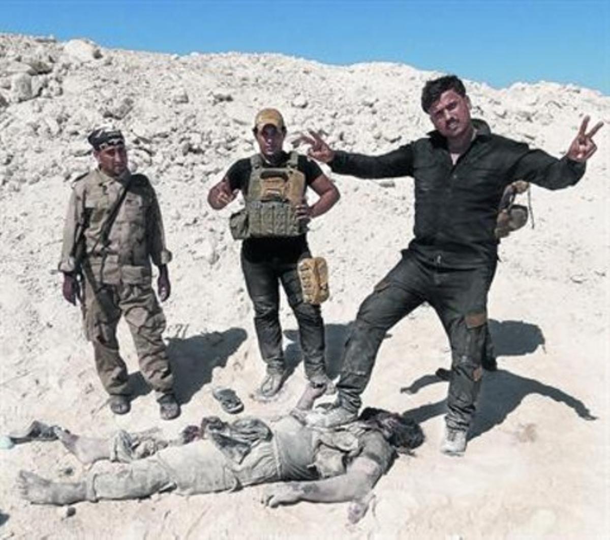 Militares iraquís y milicianos sunís posan con el cadáver de un miembro del Estado Islámico.