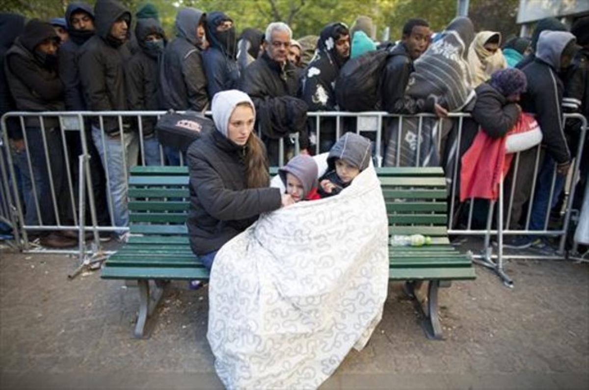 Una refugiada intenta abrigar a sus hijos mientras hace cola para ser atendida en Berlín.