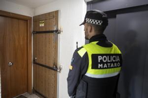 Un policía local de Mataró frente a una puerta blindada por los vecinos para impedir que sea ocupada ilegalmente.