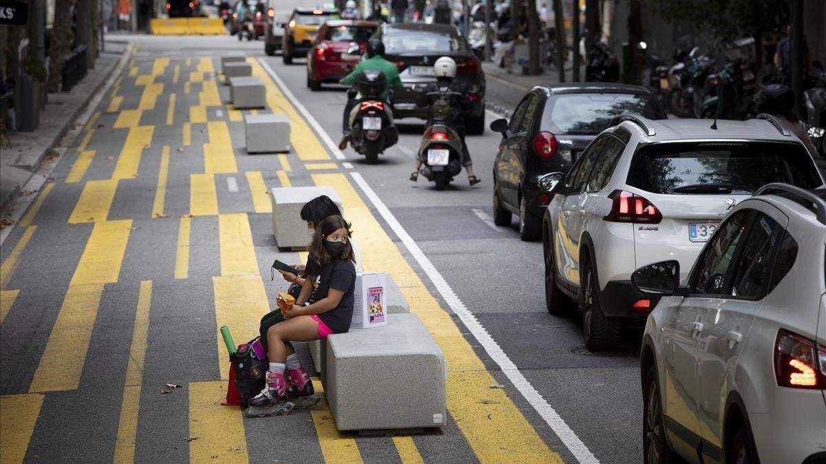 Dos niños descansan en uno de los polémicos bloques de hormigón en forma de banco ubicados en la calle de Consell de Cent. Dos niños descansan en uno de los polémicos bloques de hormigón en forma de banco ubicados en la calle de Consell de Cent.
