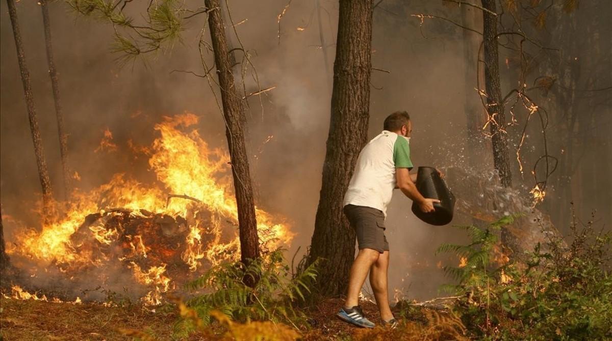 Una persona arroja agua en el incendio que afectó el domingo a la zona de Zamanes, cerca de Vigo.