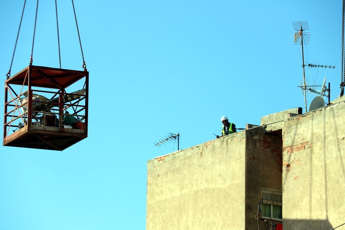 Imagen de un operario en lo alto del edificio de Badalona afectado con aluminosis en las tareas de derribo.