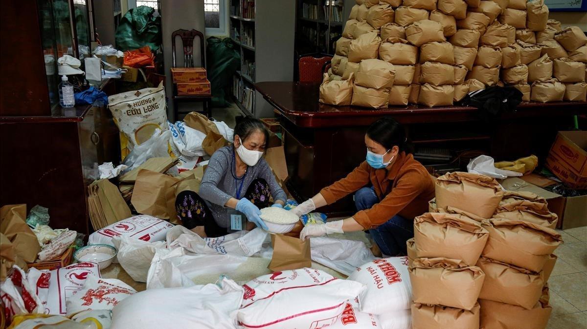 Dos mujeres empaquetan arroz para donarlo a los más vulnerables, en Hanoi.