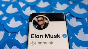 El perfil de Twitter de Elon Musk en un móvil, sobre varios logos de la red social.