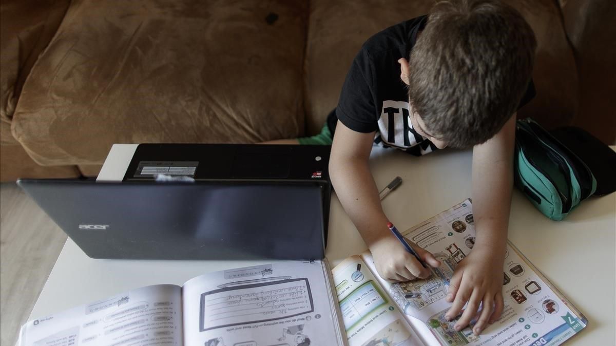 Un niño usa un ordenador como apoyo para hacer sus deberes, durante el confinamiento. Un niño usa un ordenador como apoyo para hacer sus deberes, durante el confinamiento.