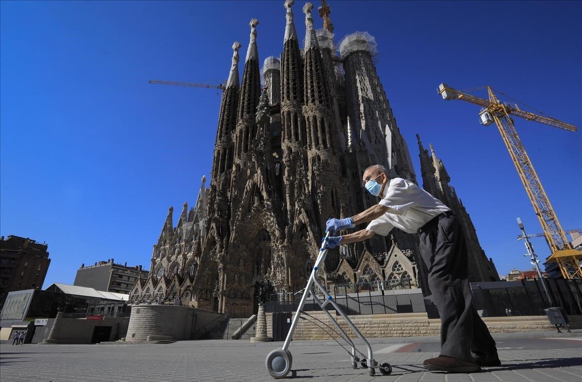 Un hombre mayor pasea en patinete ante una Sagrada Família desierta.