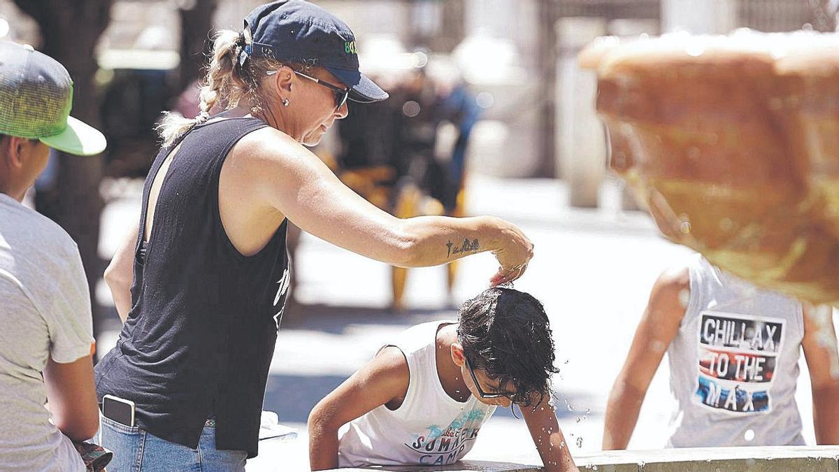 Una mujer echa agua por la cabeza a un niño en Sevilla, el pasado 7 de julio.