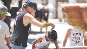 Una mujer echa agua por la cabeza a un niño en Sevilla, el pasado 7 de julio.
