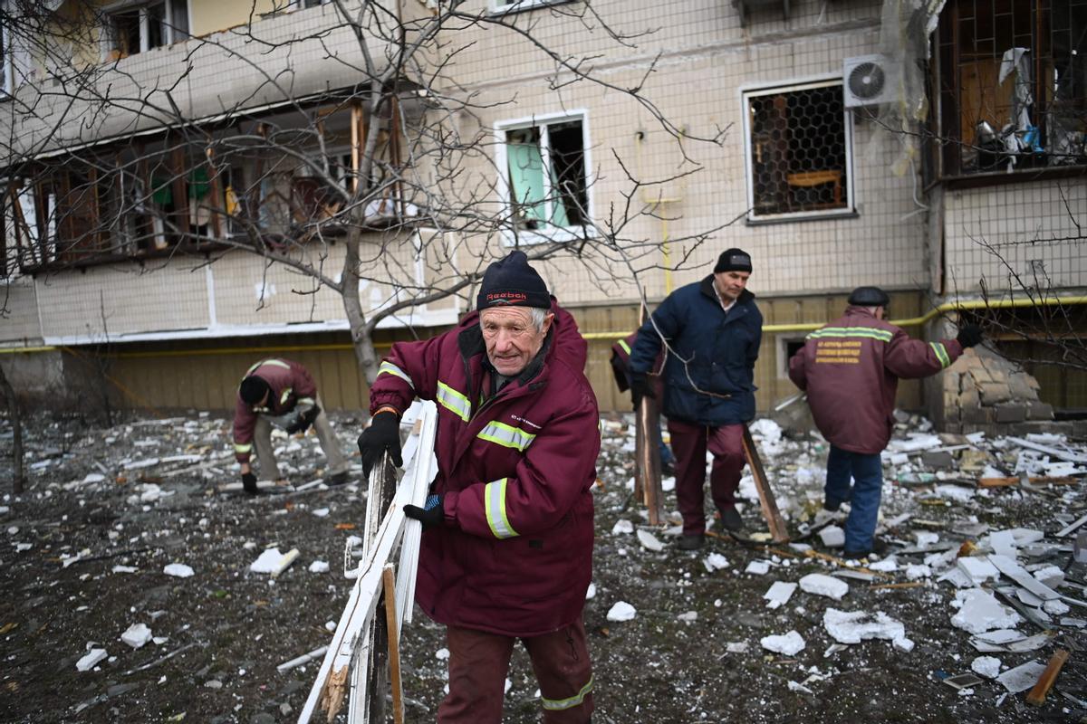 Unos hombres recogen escombros tras los ataques rusos con proyectiles en una zona residencial del Kiev.