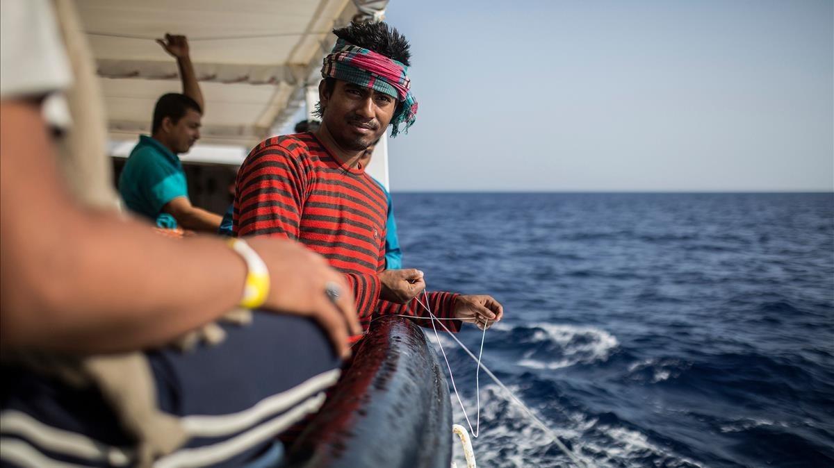 Uno de los migrantes que viajan en el Open Arms tratando de pescar, hoy domingo.